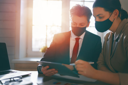 Businessman and businesswoman with medical mask working in office.の写真素材