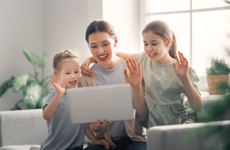 Happy loving family. Young mother and daughters girls using laptop. Funny mom and lovely children...