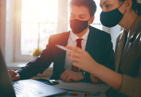 Businessman and businesswoman with medical mask working in office. Covid-19 time.の写真素材