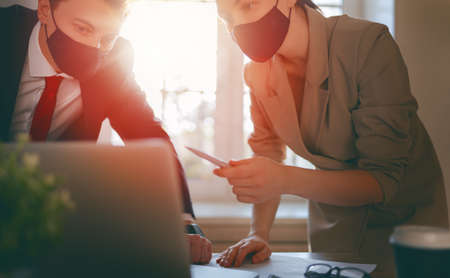 Businessman and businesswoman with medical mask working in office. Covid-19 time.
