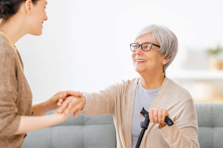 Happy patient and caregiver spending time together. Senior woman holding cane.