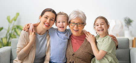 A nice girls, their mother and grandmother are hugging and  enjoying spending time together at home.