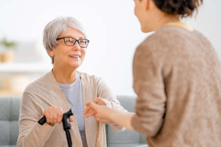 Happy patient and caregiver spending time together. Senior woman holding cane.