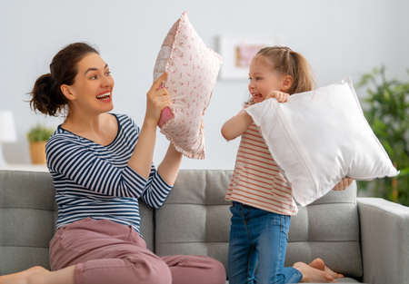 Happy loving family. The mother and her child girl are fighting pillows.の写真素材