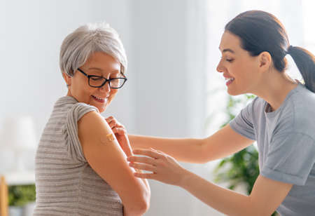 Senior woman after vaccination and her adult daughter at home. Virus protection.  .の写真素材