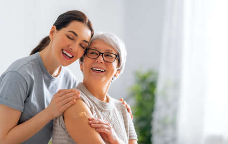 Senior woman after vaccination and her adult daughter at home. Virus protection.の写真素材