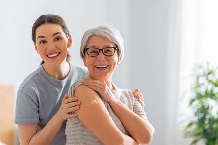 Senior woman after vaccination and her adult daughter at home. Virus protection. COVID-2019.の写真素材