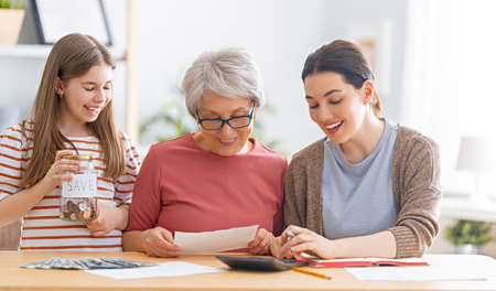 Two women and child sitting at the desk with a paper receipt, are calculating expenses, managing the...