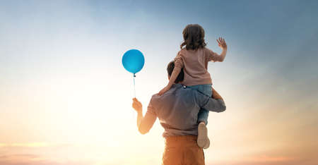 Happy loving family. Father and his daughter child playing and hugging outdoors. Cute little girl and daddy with air balloon.の写真素材