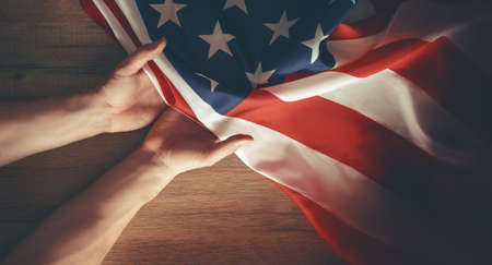 Patriotic holidays. The USA are celebrating 4th of July or Memorial Day. American flag and hands close up.の写真素材