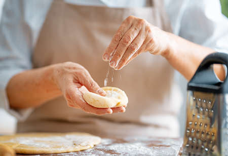 Close up view of baker is working. Homemade bread. Hands preparing dough on wooden table.