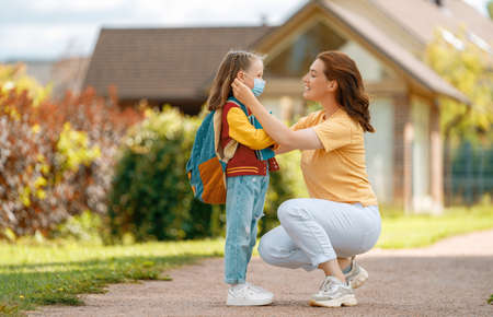 Parent and pupil of secondary school going hand in hand. Woman and girl with backpack behind the back. Beginning of lessons.の写真素材
