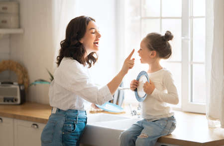 Happy day! Mom and her daughter child girl are playing, smiling in the kitchen. Family holiday and togetherness.の写真素材