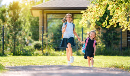 Pupils of primary school. Girls with backpacks outdoors. Beginning of lessons. First day of fall.の写真素材