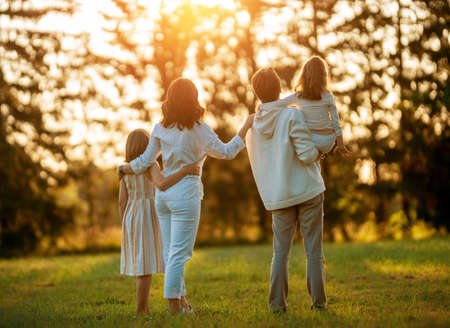 Happy family at sunset. Father, mother and children are running, having fun and enjoying summer evening.の写真素材
