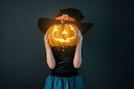 Happy Halloween! Cute little laughing girl in witch costume on black wall background.の写真素材