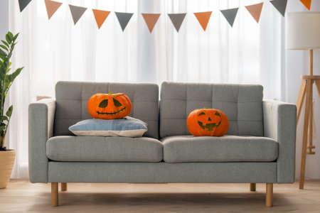 Carving pumpkin on the sofa at home. Happy family preparing for Halloween.の写真素材