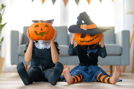 Cute little children girls in carnival costumes. Happy family preparing for Halloween. Funny kids at home.の写真素材