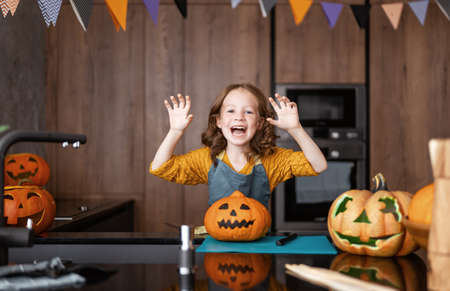 Cute little child girl with carving pumpkin. Happy family preparing for Halloween.の写真素材