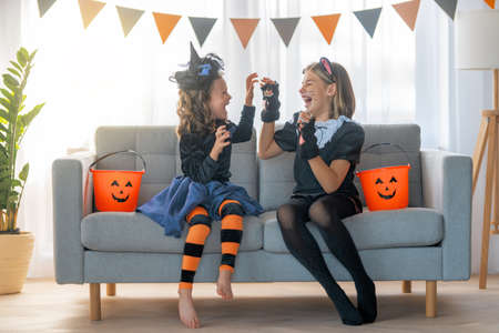 Cute little children girls in carnival costumes. Happy family preparing for Halloween. Funny kids at home.の写真素材