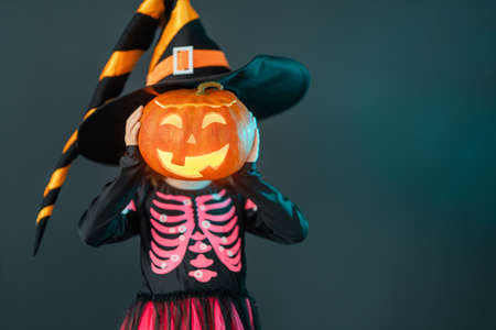 Happy Halloween! Cute little laughing girl in witch costume on black wall background.の写真素材