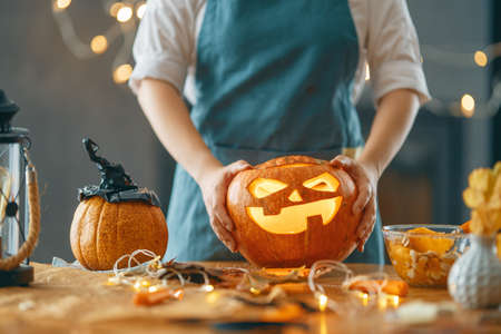 Happy Halloween! Young woman is carving pumpkin. Family preparing for holiday.の写真素材