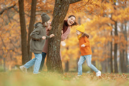 Happy family on autumn walk! Mother and daughters walking in the Park and enjoying the beautiful...