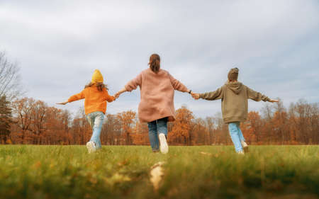 Happy family on autumn walk! Mother and daughters walking in the Park and enjoying the beautiful nature.の写真素材
