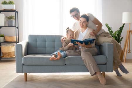 Happy loving family. Pretty young mother reading a book to her daughter.の写真素材