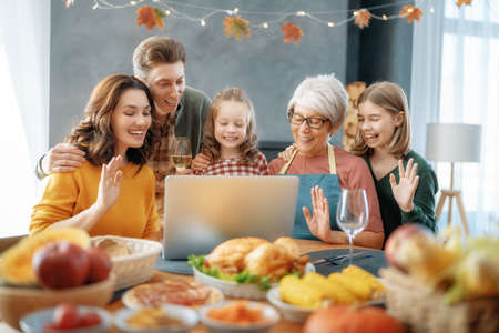 Thanksgiving Day, Autumn feast. Happy family sitting at the table, celebrating holiday and having...