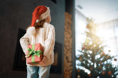 Merry Christmas and Happy Holidays! Cheerful cute child girl with gift. Kid is having fun near tree.の写真素材