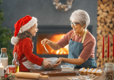 Merry Christmas and Happy Holidays. Family preparation holiday food. Grandma and granddaughter cooking cookies.の写真素材