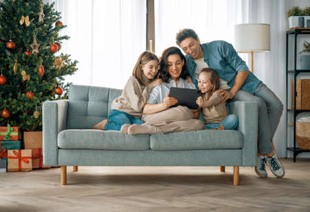 Merry Christmas! Pretty young mother, father and daughters with presents near Christmas tree.の写真素材