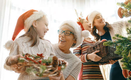 Merry Christmas and Happy Holidays. Granny, mom and daughters near the tree indoors. The morning before Xmas. Portrait of loving family.の写真素材