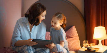 Happy loving family. Young mother and daughter girl using tablet pc. Funny mom and lovely child are having fun at home.の写真素材