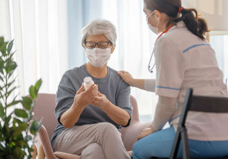 Doctor and senior woman wearing facemasks during virus and flu outbreak. Virus protection. Taking on masks.の写真素材