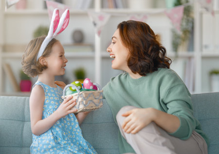 Happy holiday! Mother and her daughter with painting eggs. Family celebrating Easter. Cute little...