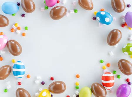 Easter holiday background. Chocolate eggs and colorful sprinkle. Top view