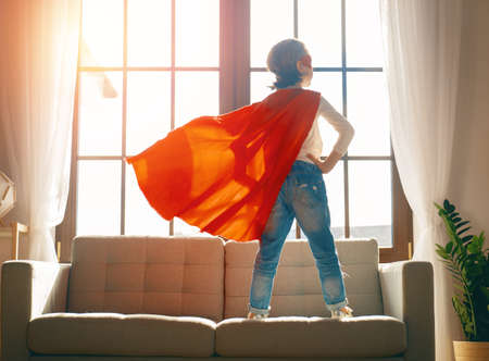 Little child is playing superhero. Kid at home. Girl power concept.