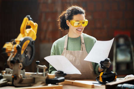 Young woman is training to be a carpenter in workshop.