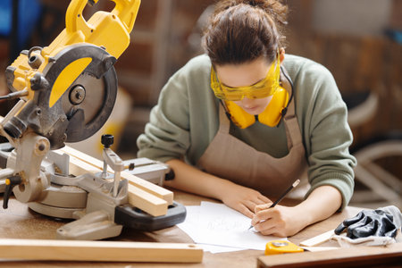 Young woman is training to be a carpenter in workshop.の写真素材