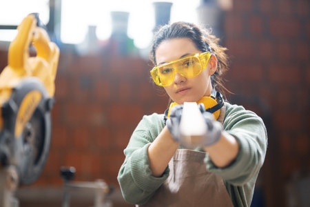 Young woman is training to be a carpenter in workshop.の写真素材