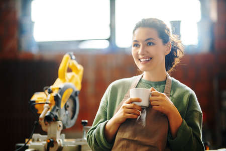 Young woman is training to be a carpenter in workshop.