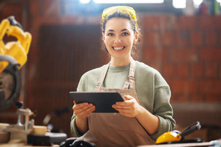 Young woman is training to be a carpenter in workshop.の写真素材