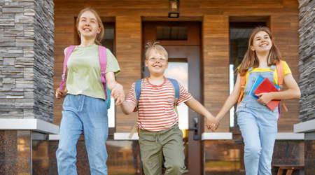 Girls and boy with backpacks outdoors. Teens are departing to school. Beginning of lessons. First day of fall.の写真素材