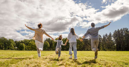 Happy family in the park. Father, mother and children are running, having fun and enjoying summer evening.の写真素材