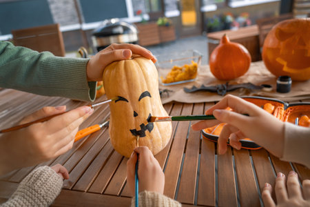 Happy family preparing for Halloween. Mother and children painting pumpkins in the backyard of the house.の写真素材