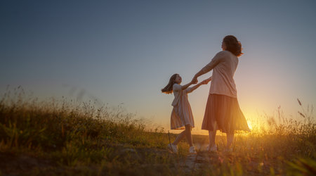 Happy family at sunset. Mother and child are running, having fun and enjoying summer evening.の写真素材