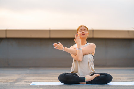 Young sportswoman is doing yoga exercise on rooftop of parking, garage in summer day morning.の写真素材