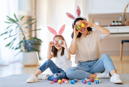 Happy holiday. Mother and her daughter with painting eggs. Family celebrating Easter. Cute little...